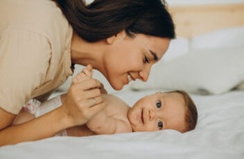 Mother with baby daughter lying on bed